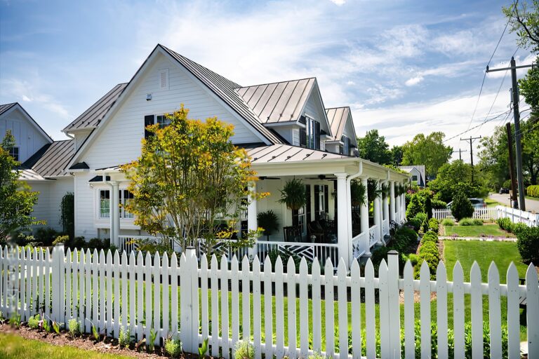 Freshly painted white picket fence in front of a two-story home