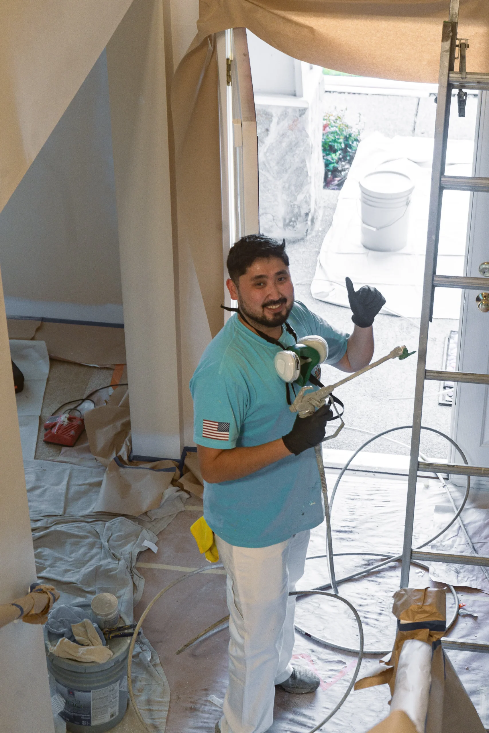 Residential Interior Painting with Sprayer A professional painter with a sprayer gives a thumbs up, ready for interior painting