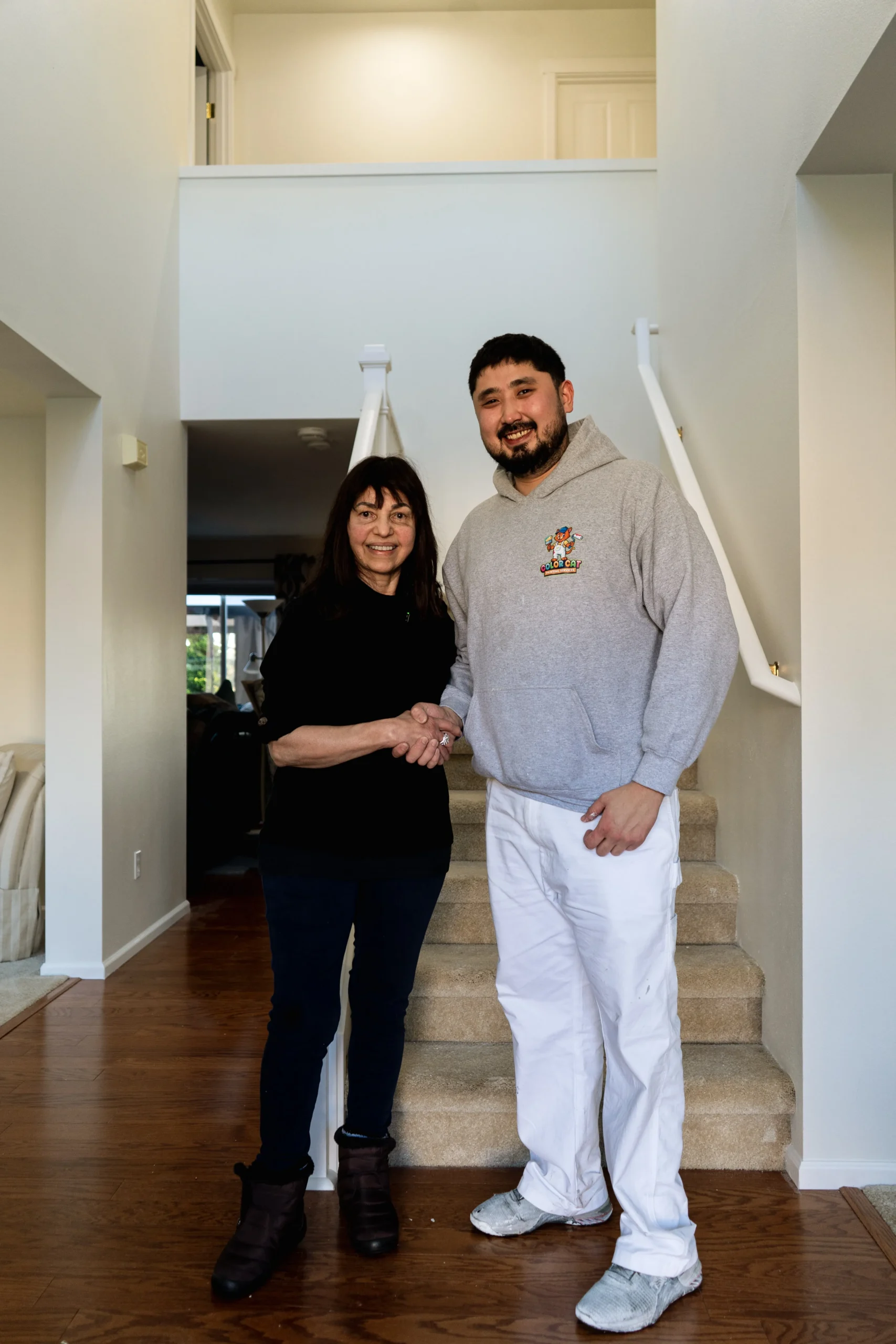 Seattle Residential Interior Painting Project Completion A professional painter shakes hands with a satisfied client after an interior painting project in Washington.