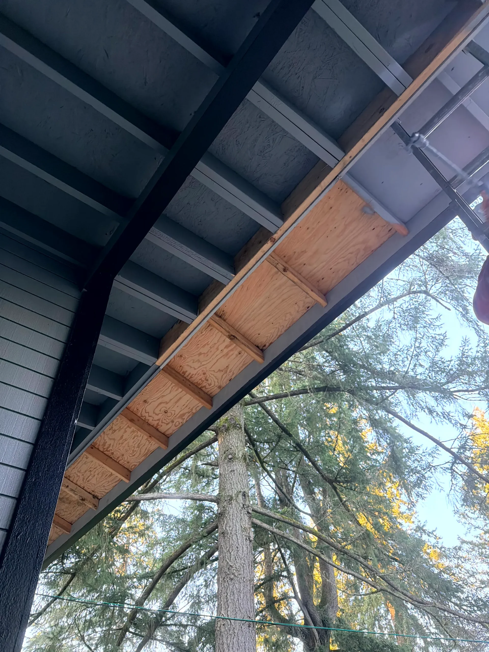 Outdoor Wood Structure Painting and Staining Underside view of a wooden outdoor structure, possibly a deck or balcony, ready for painting or staining.