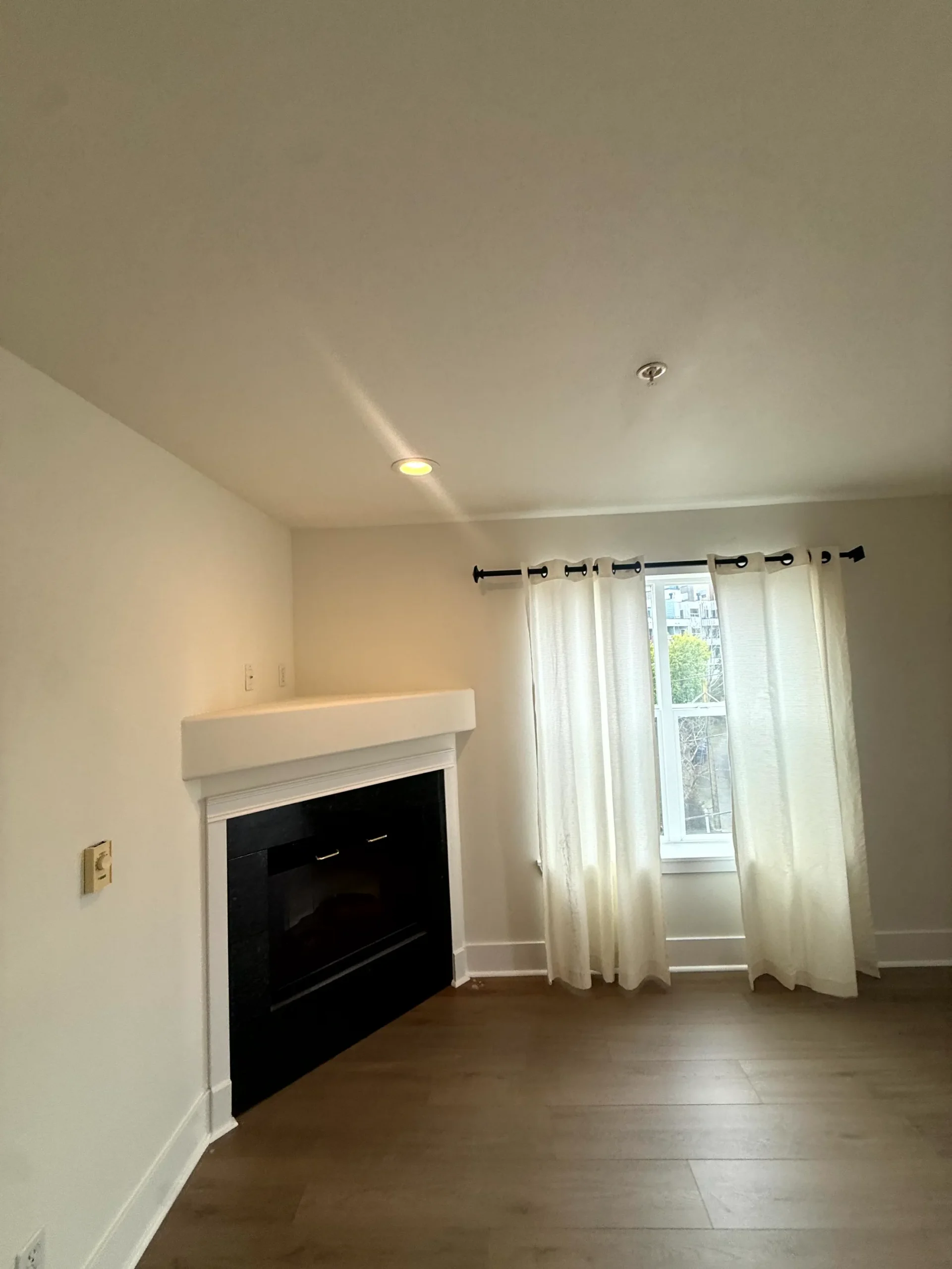 Residential Interior Painting with Fireplace Accent Clean, empty living room with light painted walls, a modern fireplace, and hardwood floors.