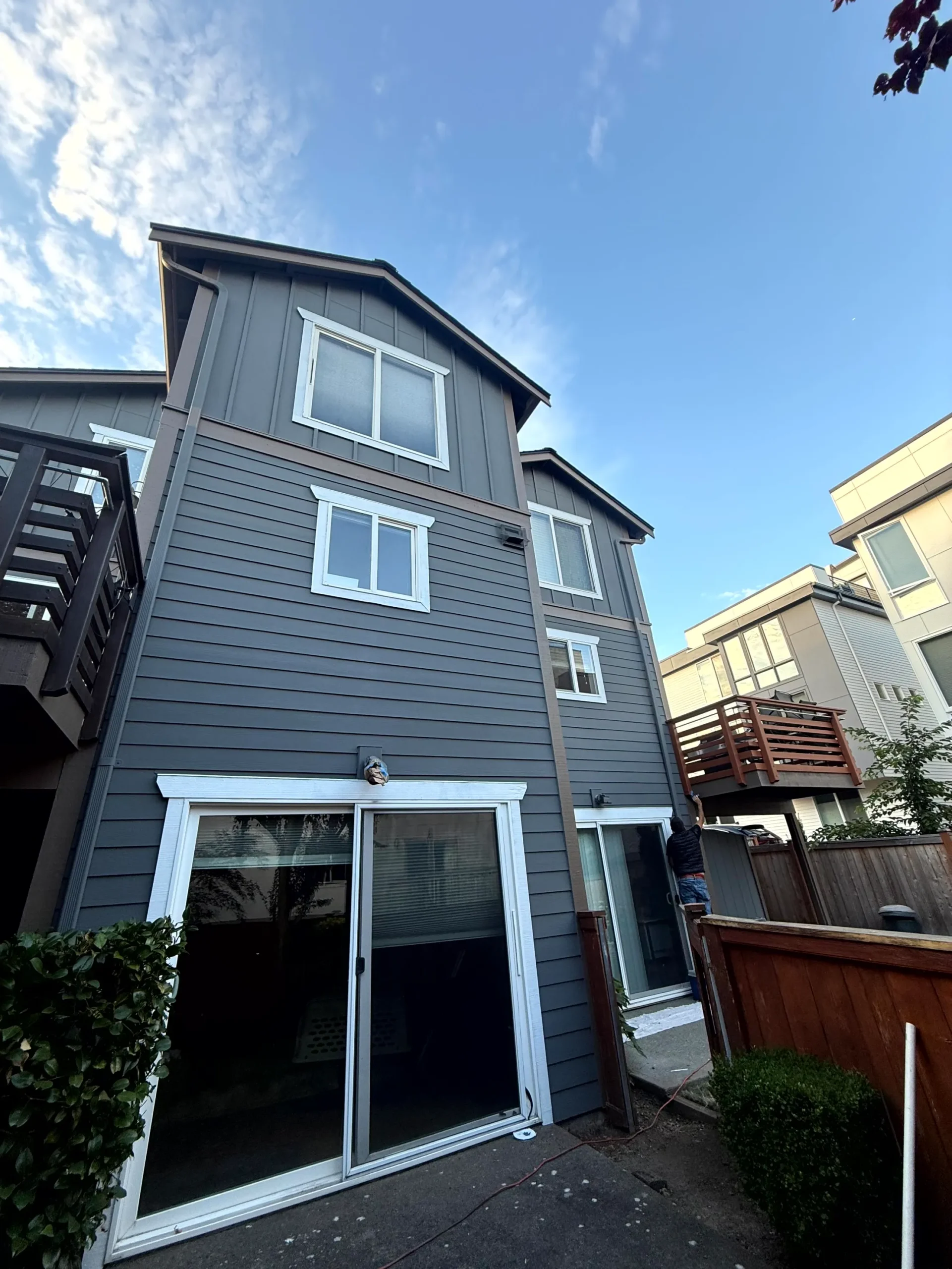 Complete Exterior House Painting A modern multi story house with fresh dark grey exterior paint and white trim