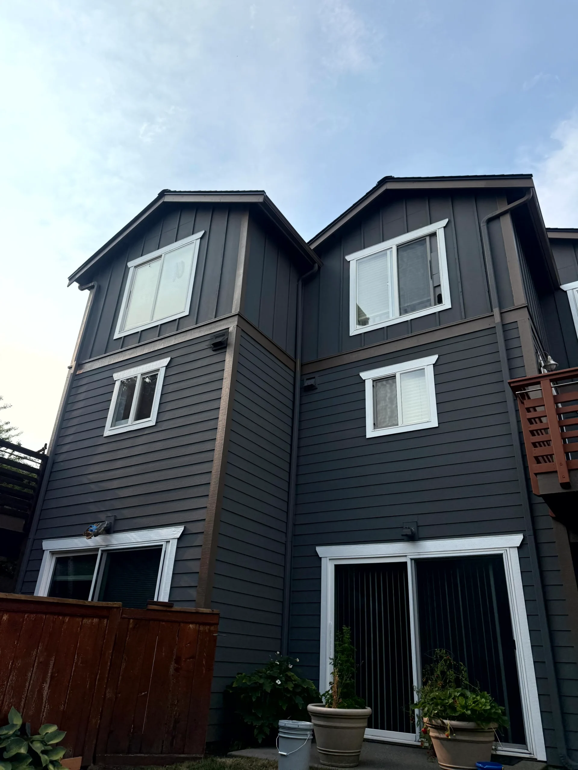 Multi Story Residential Exterior Painting with Dark Siding Exterior view of a multi story residential building with dark gray siding and white window trim.
