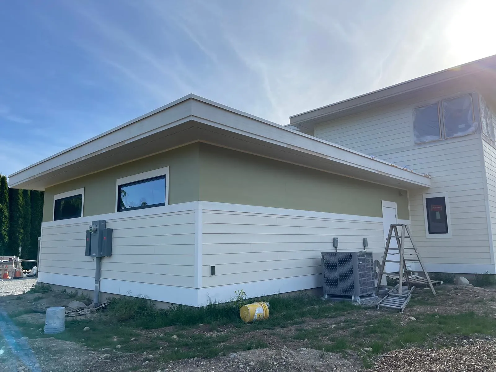 Residential Exterior Painting for New Construction Homes Side view of a newly painted modern home exterior with light siding and green accents.