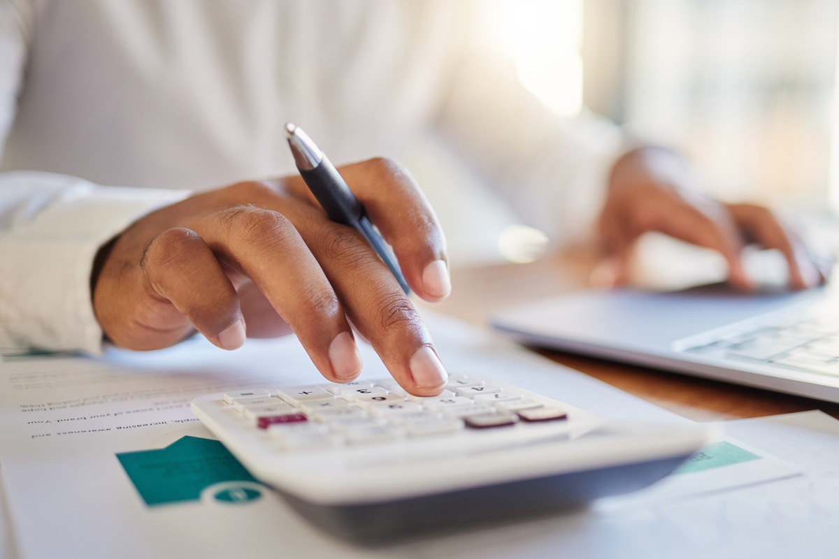 Finance, accounting and fintech, a man on a computer and calculator working out his business budget strategy. Businessman at his office desk, laptop, money management and financial investment online.